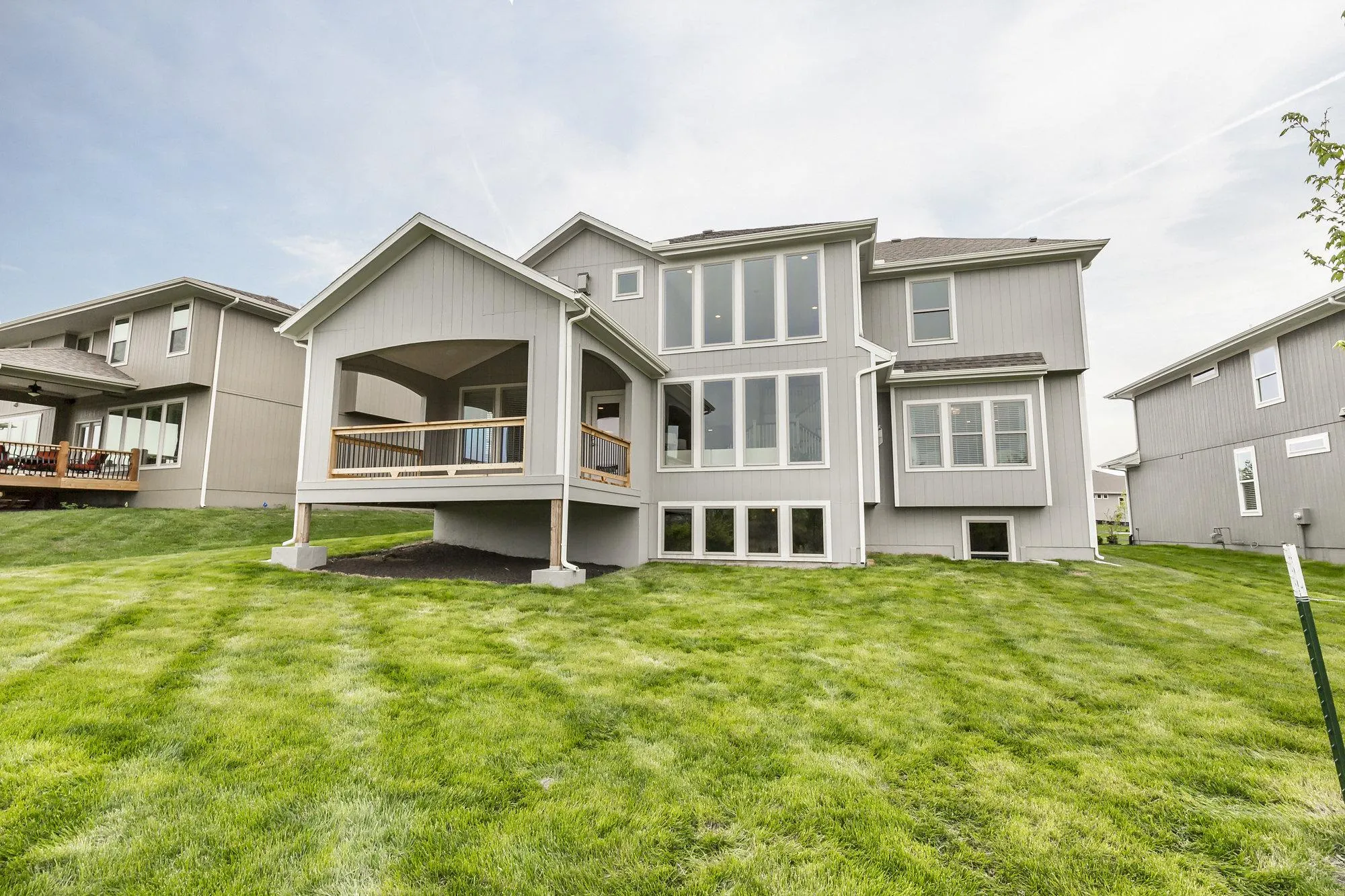 Modern grey townhomes with large windows and balconies, viewed from the yard.