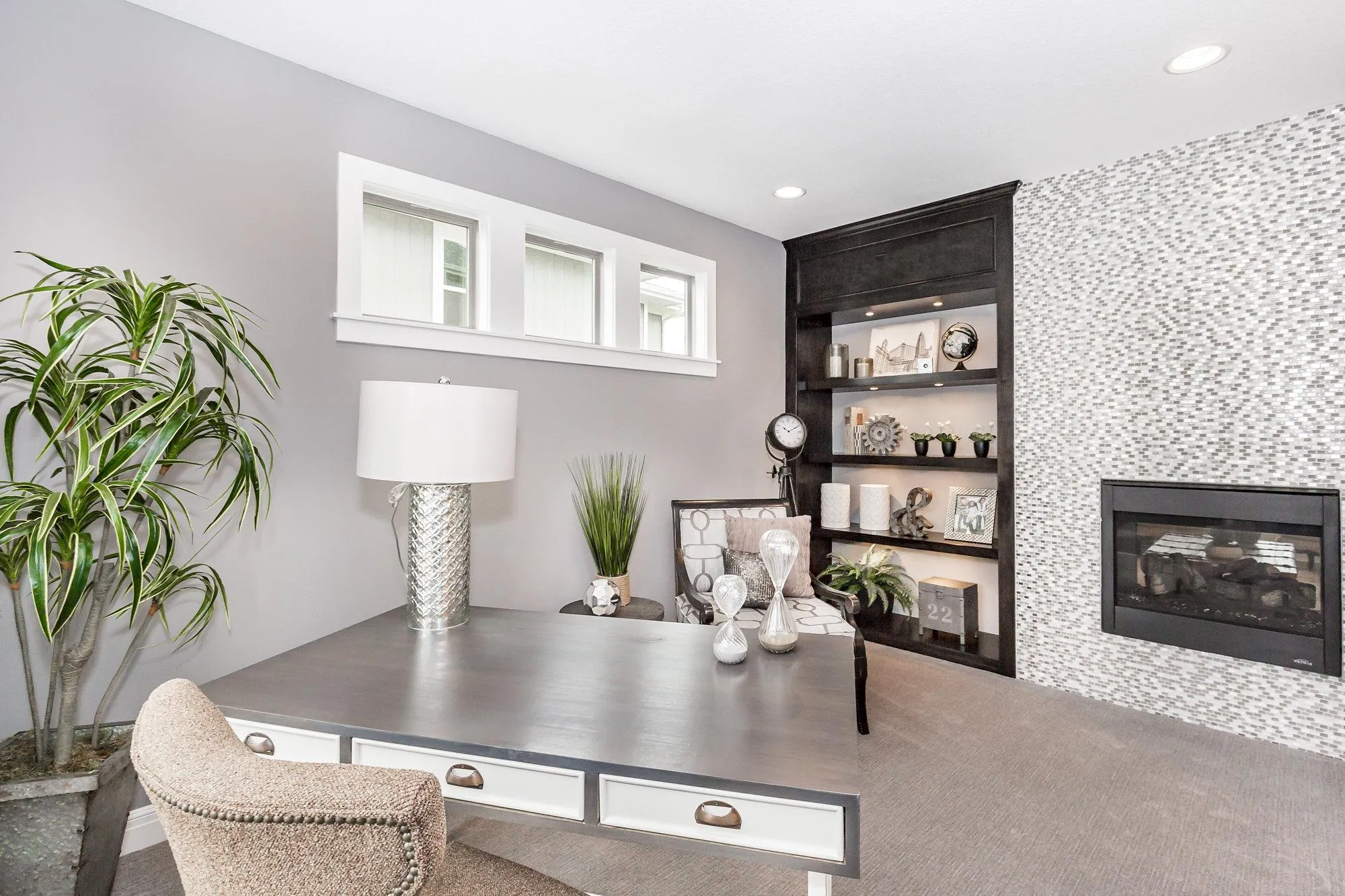 Contemporary living room with a raised gray platform, black built-in shelves, a mosaic wall, and a fireplace on the right side.