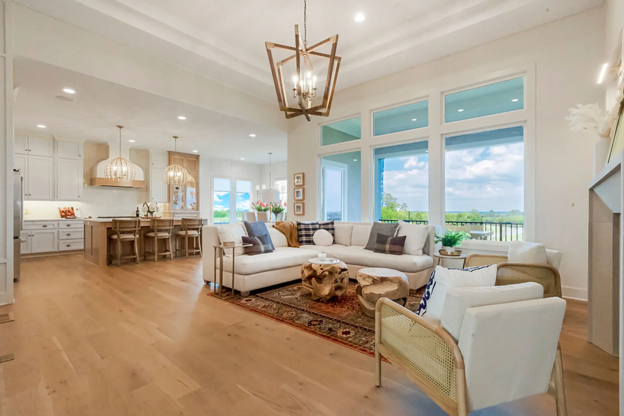 Bright open-concept living space with white cabinetry, oak island, and a geometric chandelier.