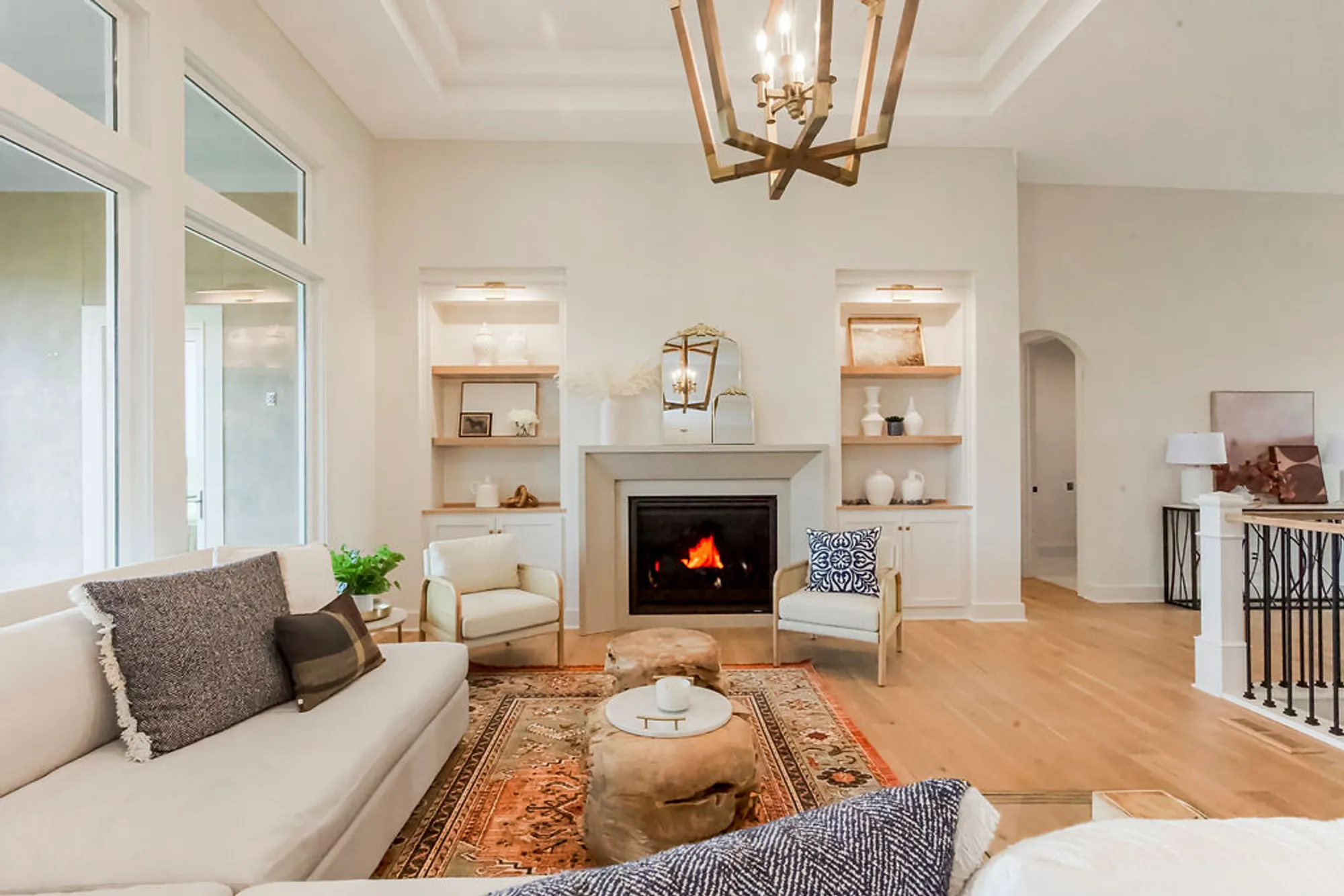 Bright living room with a lit fireplace, cream sofa, and built-in shelves flanking the mantel