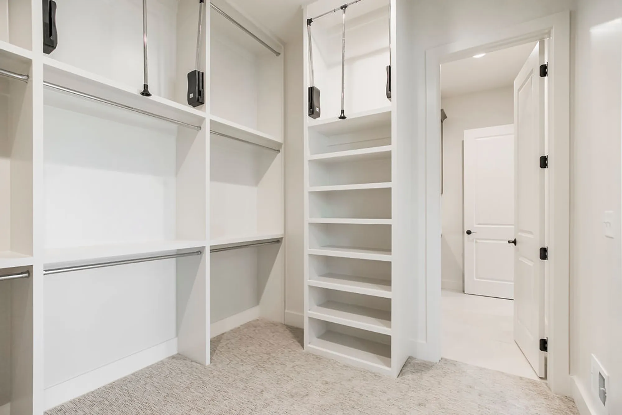 Bright white walk‑in closet with built-in shelving, hanging rods, and a tall cubby tower for storage.