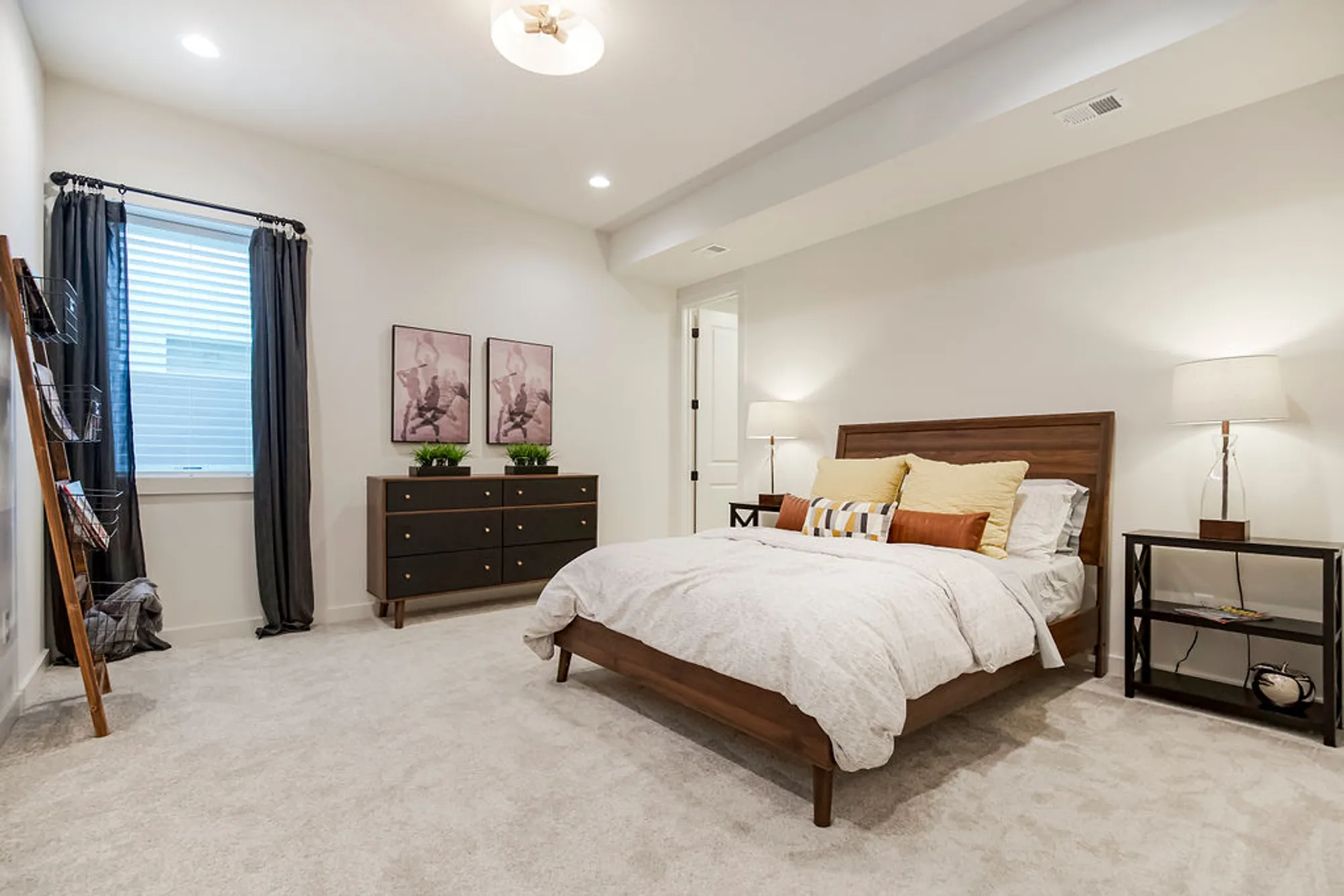 Bedroom with a wooden platform bed, two nightstands, and a black dresser in a bright, modern space